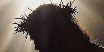 Silhouette of Jesus Christ with crown of thorns and radiant light symbolizing His sacrifice and resurrection, representing the true meaning of Easter in 2025