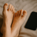 Digital illustration of feet near a smartphone, representing selling feet pictures online for money